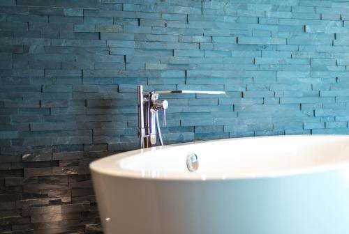 a bathroom with a white tub and a blue brick wall at Superior Hotel Nidwaldnerhof in Beckenried