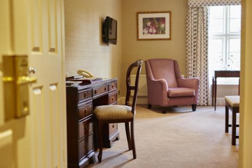 a room with a chair and a dresser and a chair at Tylney Hall Hotel in Hook