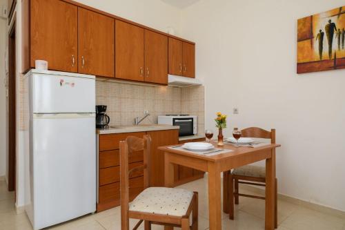 eine Küche mit einem weißen Kühlschrank und einem Tisch mit Stühlen in der Unterkunft Coral Sea Studio in Kokkinos Pyrgos