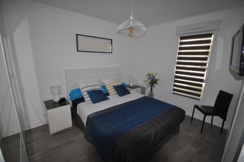 Un dormitorio con una cama con almohadas azules y una ventana en Dervenn Mor, en Sarzeau