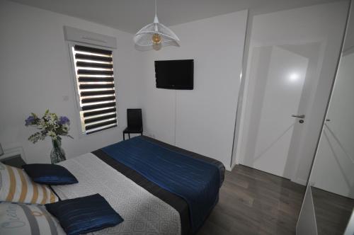 a bedroom with a bed with blue sheets and a window at Dervenn Mor in Sarzeau