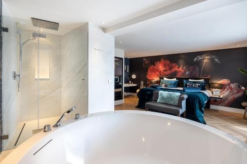 a bathroom with a bath tub and a bedroom at Van der Valk Hotel Leiden in Leiden