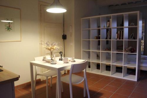 een witte tafel met stoelen en een boekenplank bij appartamento San Tommaso in Lucca