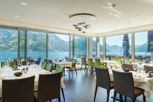 a dining room with tables and chairs and windows at Superior Hotel Nidwaldnerhof in Beckenried