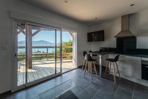 une cuisine avec un comptoir et des tabourets en face d'un balcon dans l'établissement T2 vue sur le golfe d'Ajaccio, à Porticcio
