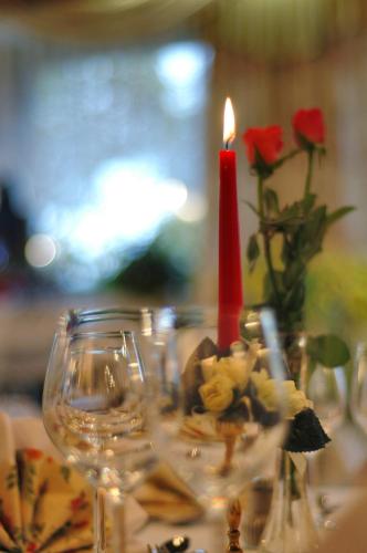 a candle sitting on a table with glasses and roses at Hotel Dreisonnenberg in Neuschönau