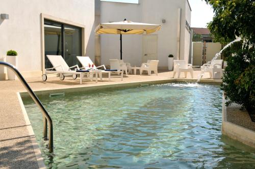 a pool with an umbrella and chairs and a table at Hotel Del Conte in Fondi