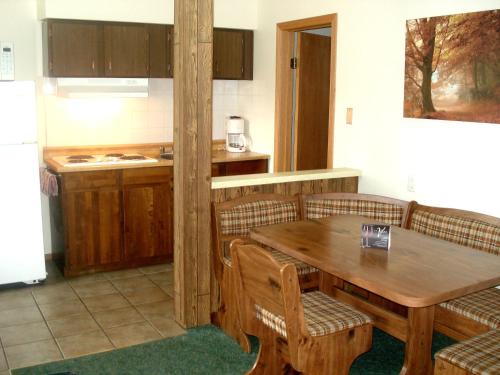 a kitchen with a wooden table and chairs and a kitchen with a refrigerator at Motel Tyrol in Radium Hot Springs