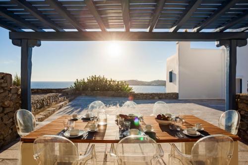 un tavolo e sedie in legno su un patio con vista sull'oceano di AGL Luxury Villas a Mykonos Città
