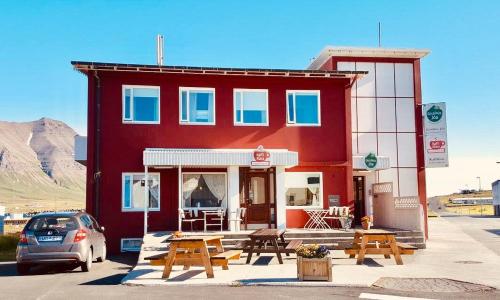 a red building with picnic tables in front of it at Klara Guesthouse in Ólafsfjörður