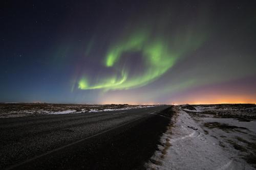 an empty road with the aurora in the sky at Villa - South Iceland in Laugaras