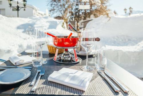 a table with glasses and a red bowl on it at Hotel-Restaurant Bellevue in Flims