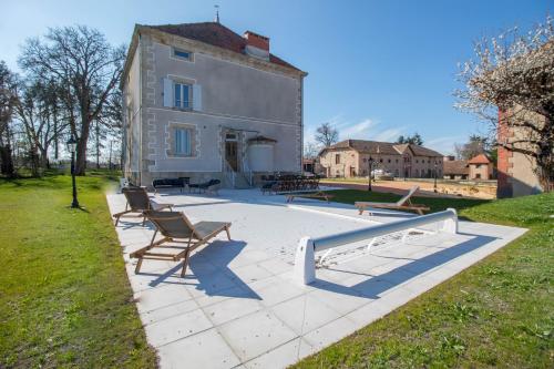 a group of benches sitting on a patio in front of a building at Gite de charme 5 épis - Demeure La Moliére in Glaine-Montaigut