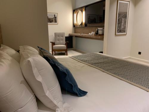 a bedroom with a bed with pillows and a chair at El Boutique Hotel in Soûr