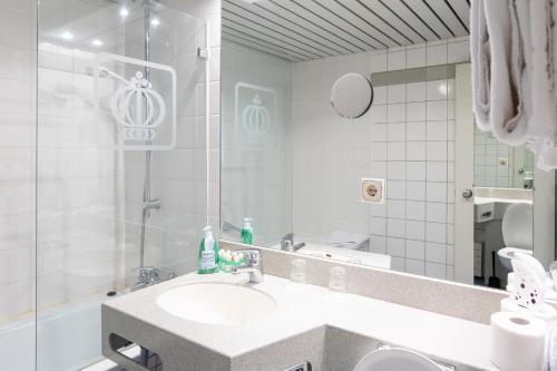 a white bathroom with a sink and a shower at Hotel Königshof The Arthouse in Cologne