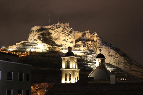 a building with a mountain in the background at night at Mendez Nuñez Alicante in Alicante