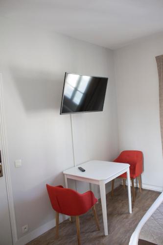 a room with a white table and two red chairs at Hotel Le Reynita in Trouville-sur-Mer