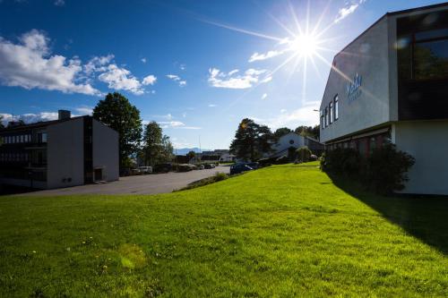 a building on a green field next to a building at Molde Vandrerhjem Hostel in Molde