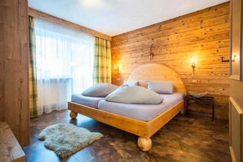 1 dormitorio con 1 cama con pared de madera en Alpen Apartments Austria, en Berwang