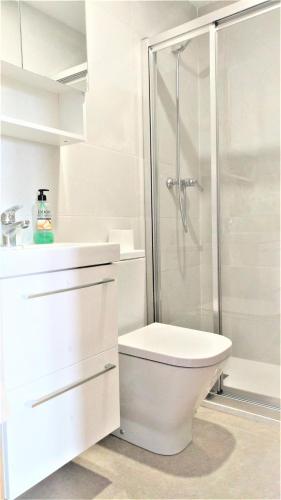 a white bathroom with a shower and a toilet at Residencial Olival-Acceso privado playa por jardín in Oliva
