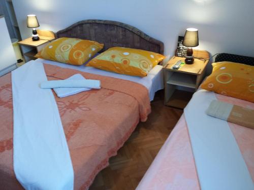 two beds in a small room with two lamps at Apartments & Hostel Zdrava Hrana in Mostar