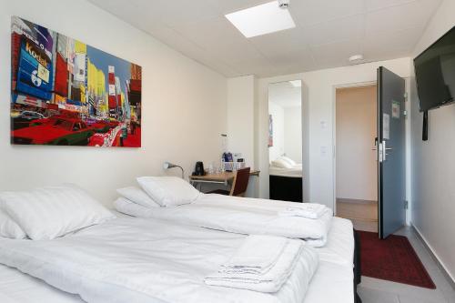duas camas brancas num quarto com uma pintura na parede em Kalmar Hotell em Kalmar