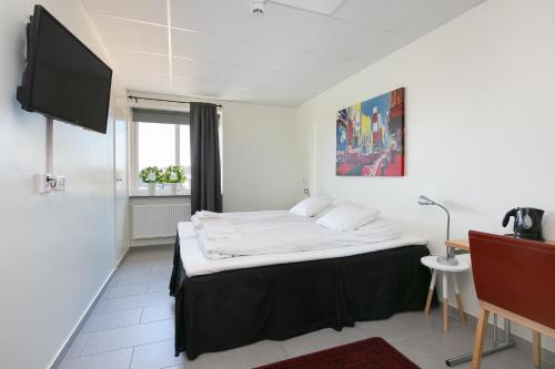Kalmar Hotell في كالمار: غرفة نوم مع سرير كبير وتلفزيون على الحائط
