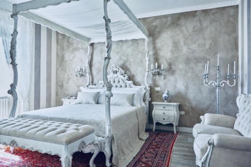 La Zarabba Boutique Hotel في بونتي سول مينشيو: غرفة نوم مع سرير مغطى أبيض وأريكة