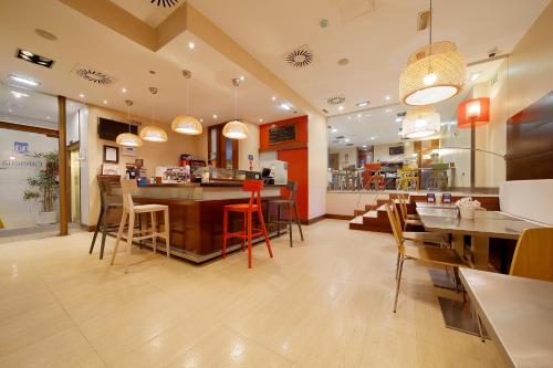 a restaurant with a bar and tables and chairs at Hotel Marqués, Blue Hoteles in Gijón