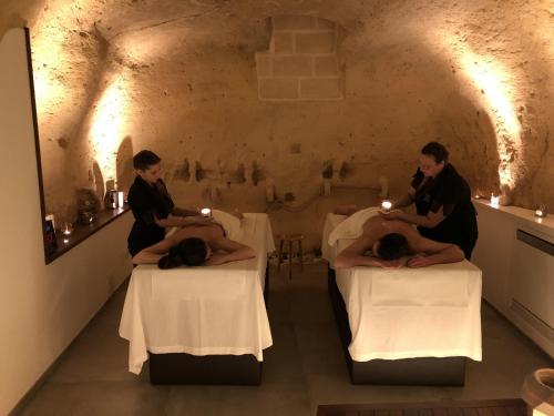 Dos personas sentadas en las camas en una habitación con velas en Le Fornaci Imperial Lodge & Spa, en Gravina in Puglia