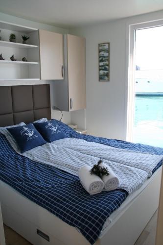 a bedroom with a bed with two towels and a window at Floating House Marina Royal in Portorož