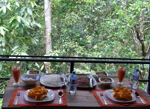 a wooden table with food and drinks on it at Sinharaja Kurulu Ella Eco Resort in Deniyaya