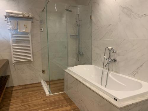 a bathroom with a tub and a glass shower at El Boutique Hotel in Soûr