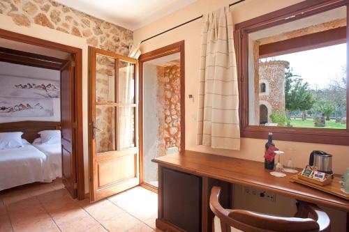 a bedroom with a bed and a desk and a window at Agroturismo Es Quatre Cantons in Binissalem