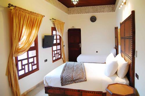 a bedroom with a bed and two windows at Riad Fes Aicha & SPA in Fès