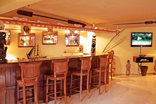 a bar with wooden stools in a room at Tanah Merah Art Resort by AGATA in Ubud
