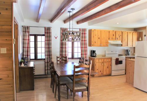 una cocina con armarios de madera y una mesa con sillas. en Chalet Rustique CRDS Tremblant, en Lac-Supérieur