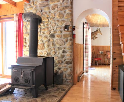a wood stove in a room with a stone wall at Chalet Rustique CRDS Tremblant in Lac-Superieur