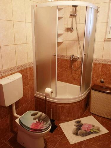 a bathroom with a shower and a toilet with flowers on it at Apartman Roza in Ploče