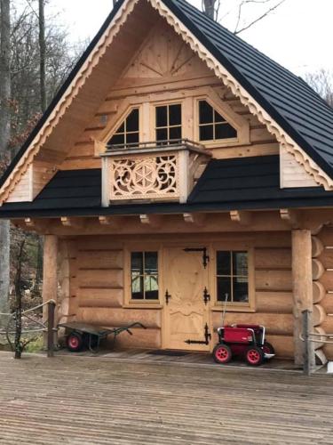 una cabaña de madera con un coche rojo estacionado frente a ella en Swiss Chalet en Steninge