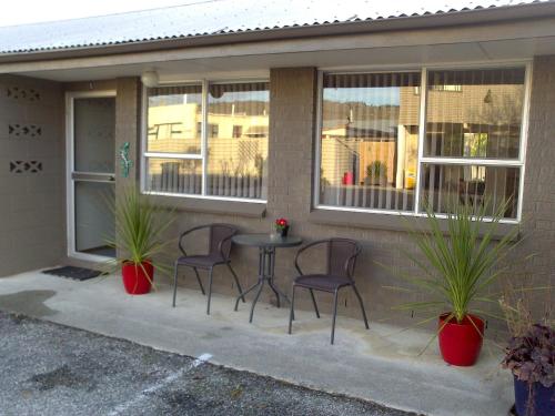 a patio with chairs and a table in front of a house at Almond Court Motel in Alexandra