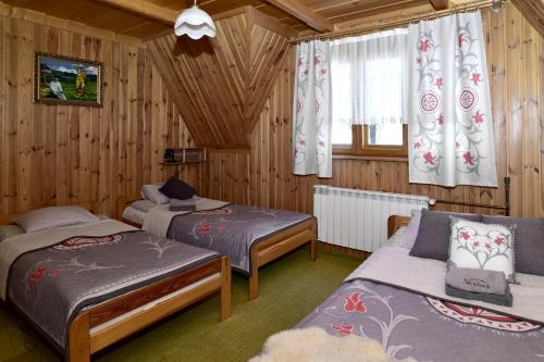 two beds in a room with wooden walls at Na ubocy in Brzegi