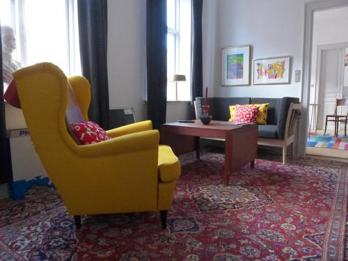 a living room with a yellow chair and a table at Sortebrødregade Ferielejligheder in Ribe