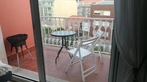 Habitación con vistas a un balcón con mesa y sillas. en Apartamento de playa, en Boiro