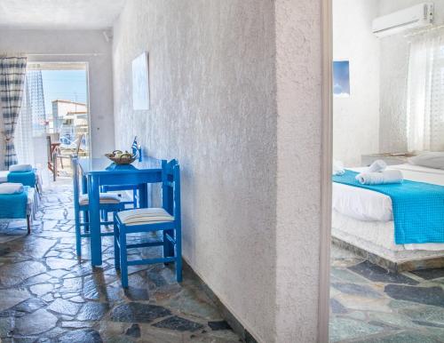 - une table bleue et des chaises dans une chambre avec un lit dans l'établissement Phoenix Beachside Condos, à Kokóni