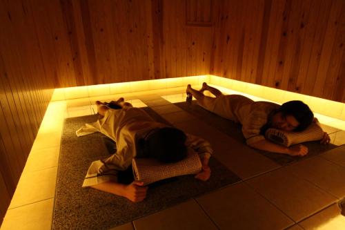 two people laying on the floor in a room at Aburaya Tousen in Yamanouchi