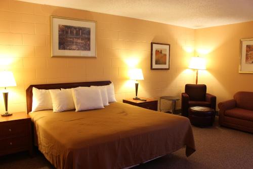 um quarto de hotel com uma cama, uma cadeira e candeeiros em Sunlac Inn Lakota em Lakota