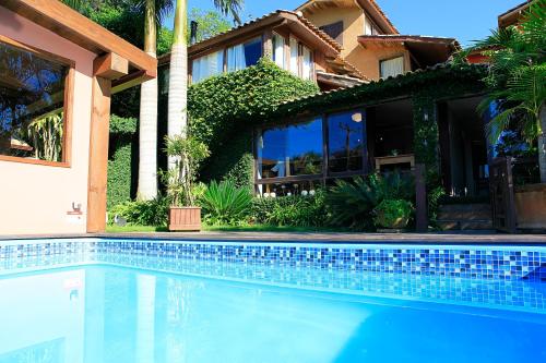 a house with a swimming pool in front of a house at Pousada Vigia Das Marés in Praia do Rosa