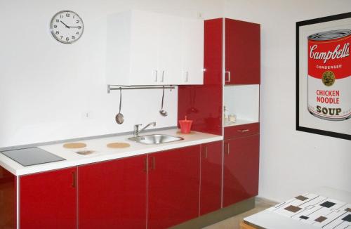 a kitchen with red cabinets and a sink and a clock at Visa Residence in Bari