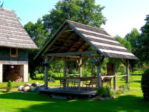 a gazebo with a table and benches in a yard at Griķi in Kalnišķi